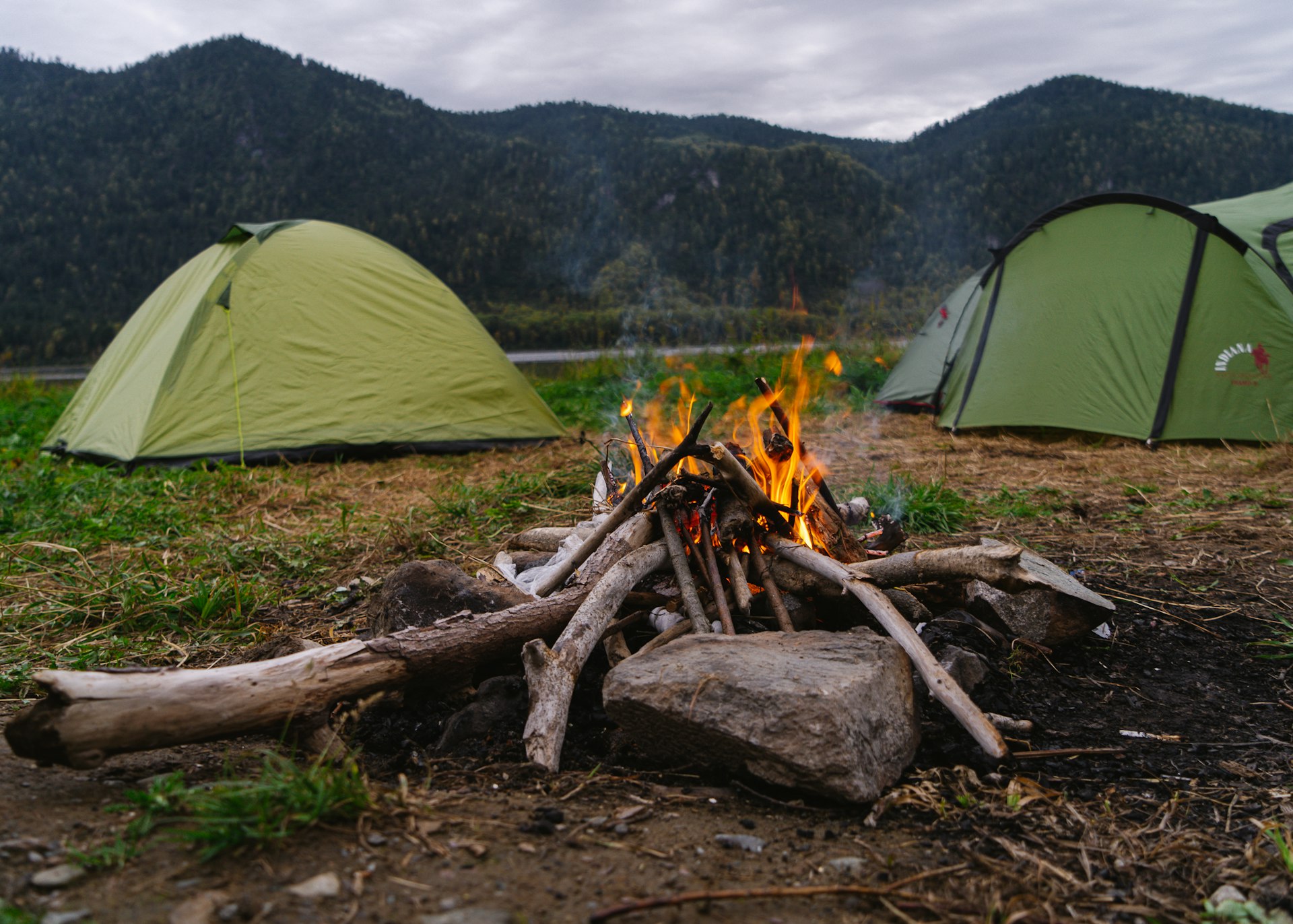 a camp site with a camp fire and tents in the background